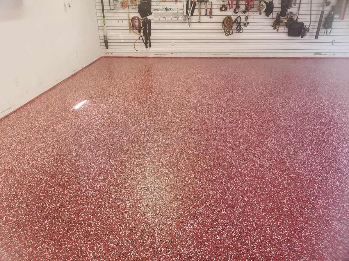 Home garage with a red flake epoxy floor and tools hung on the wall