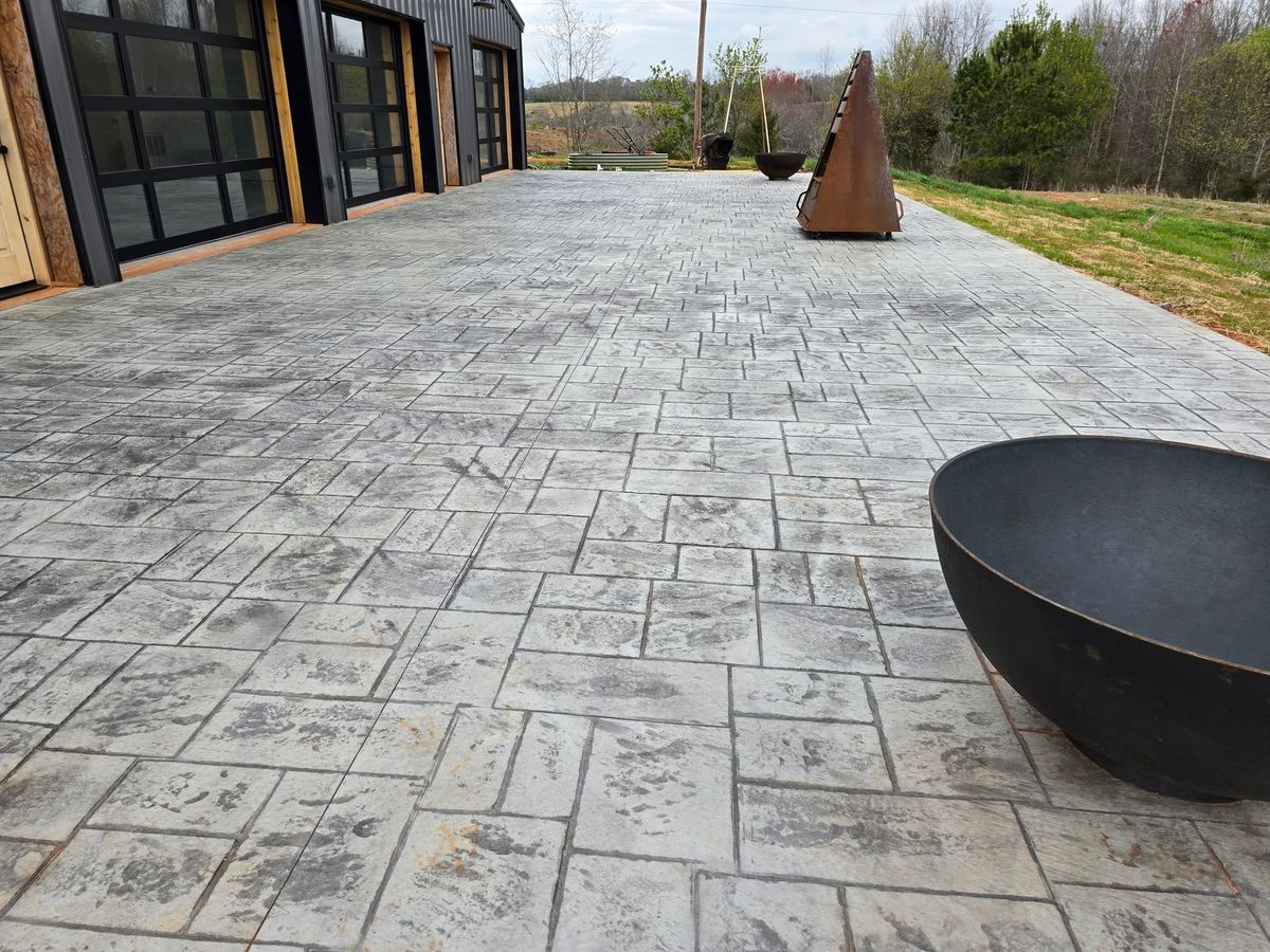 Fire pit sitting on a stamped concrete patio beside a glass-walled room