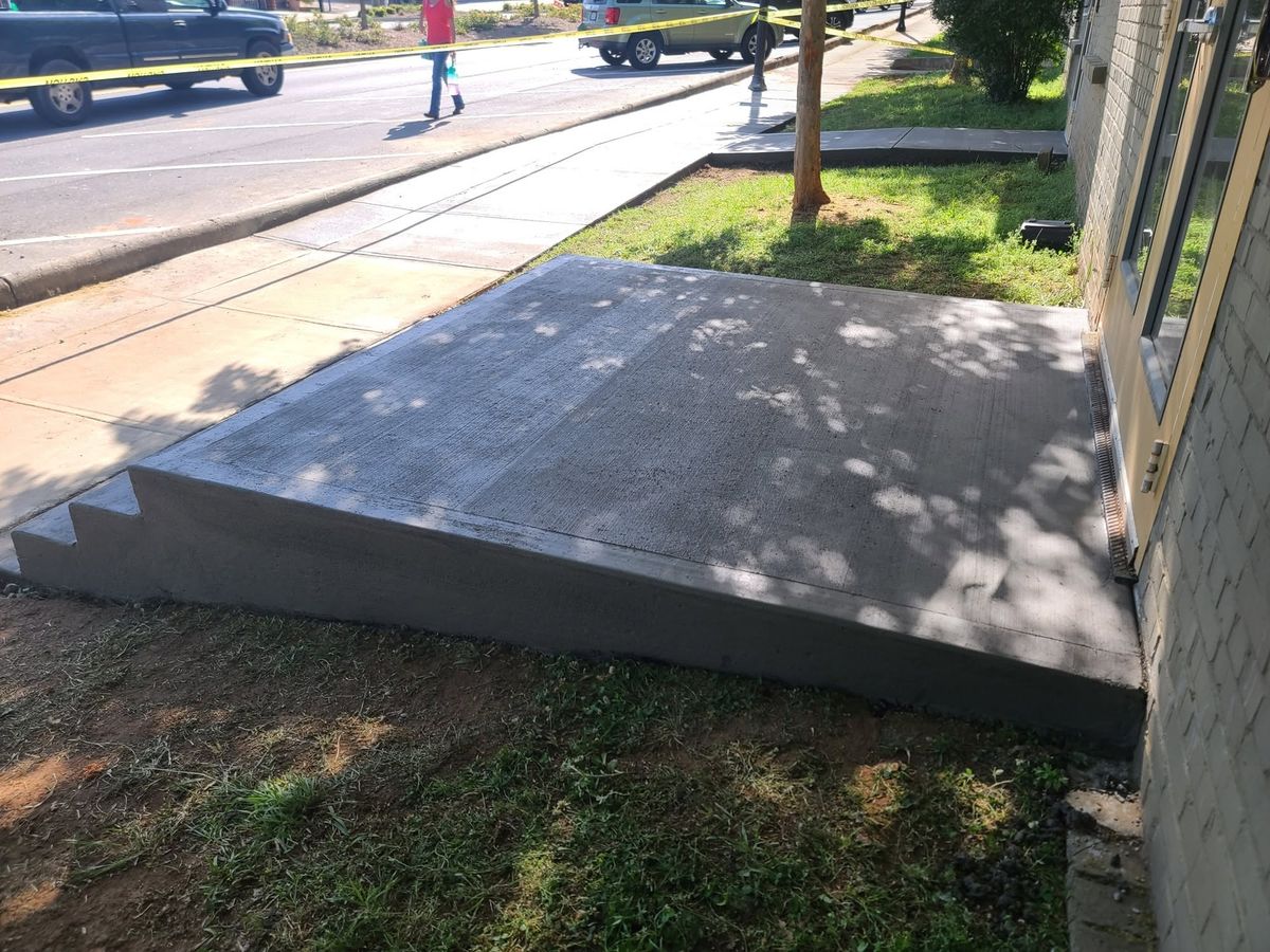 Fresh concrete landing and steps at a downtown storefront behind caution tape