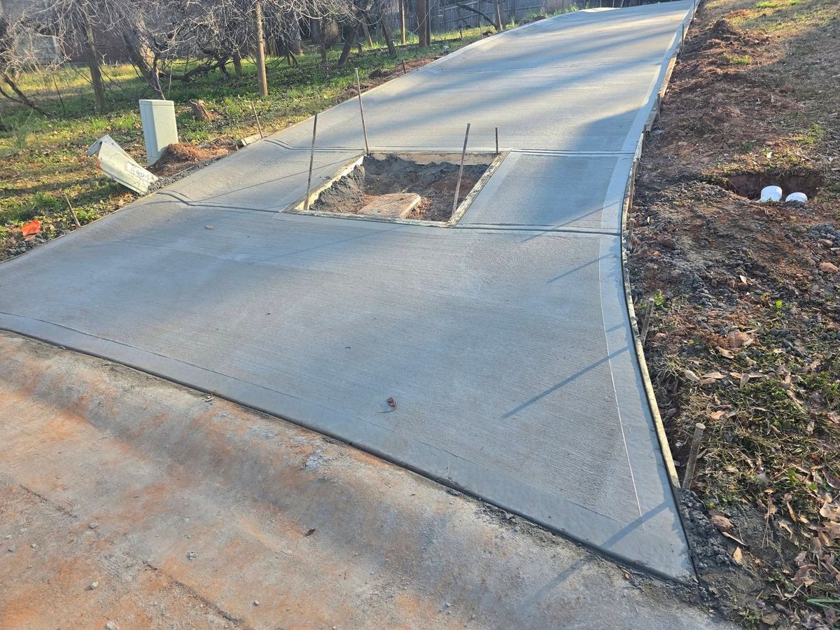 Concrete driveway rising up a wooded hillside lot