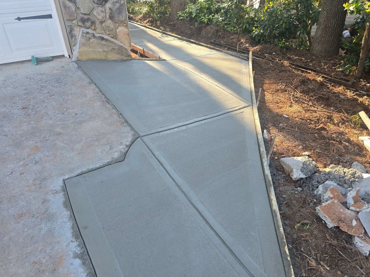Sloped concrete driveway beside a wooded yard