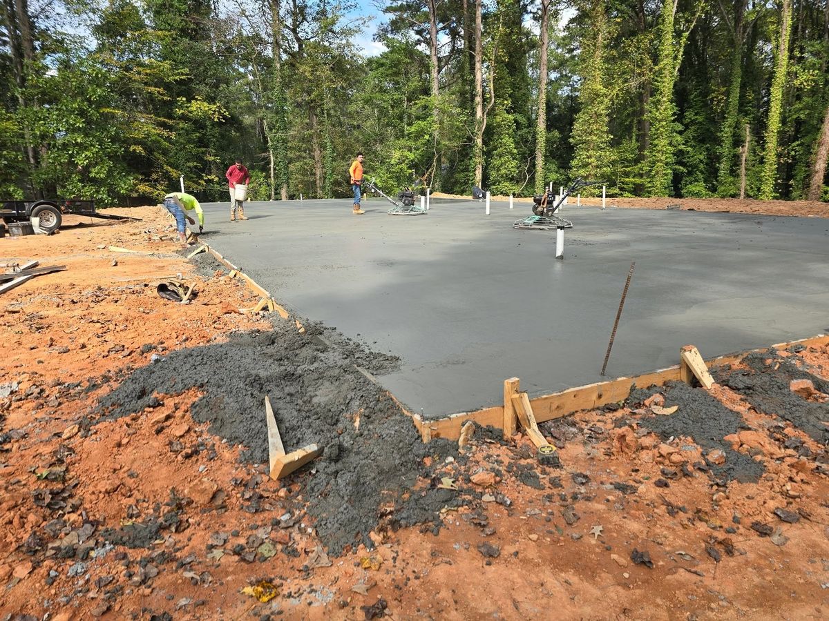 Workers screeding wet concrete on a slab pour in the woods