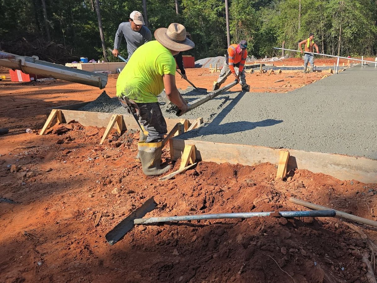 Screed board being drawn over wet concrete by two workers on the forms