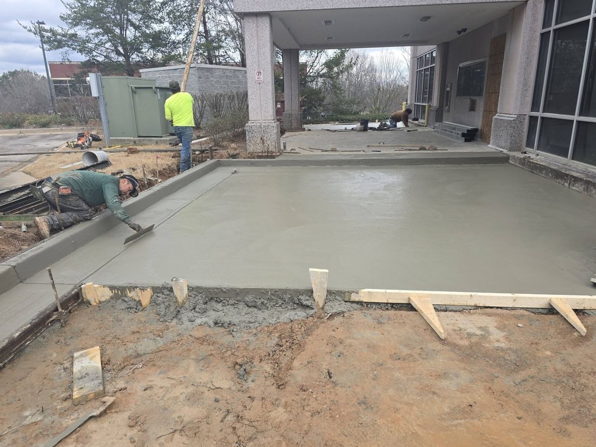 Crew finishing a commercial concrete slab under a building canopy