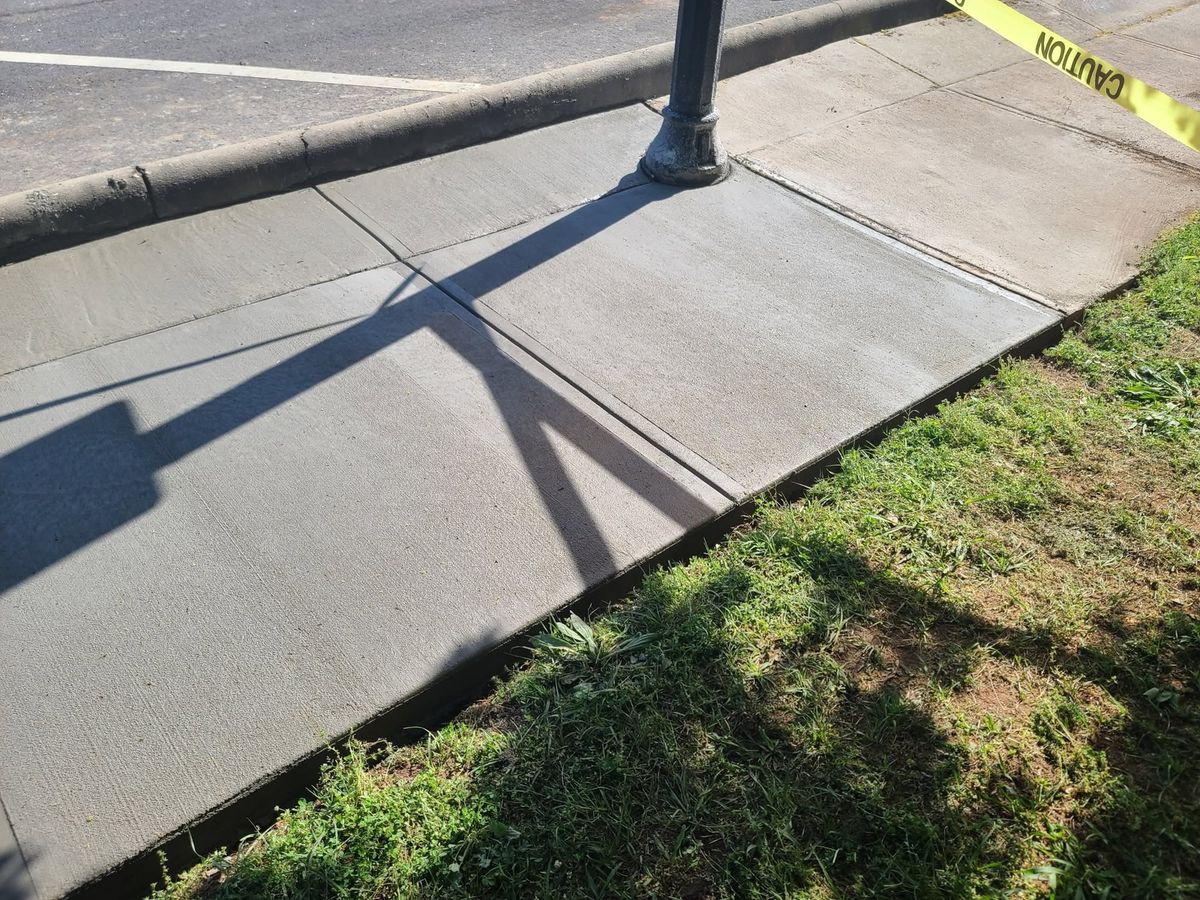 Fresh concrete sidewalk at the curb around a street lamp base