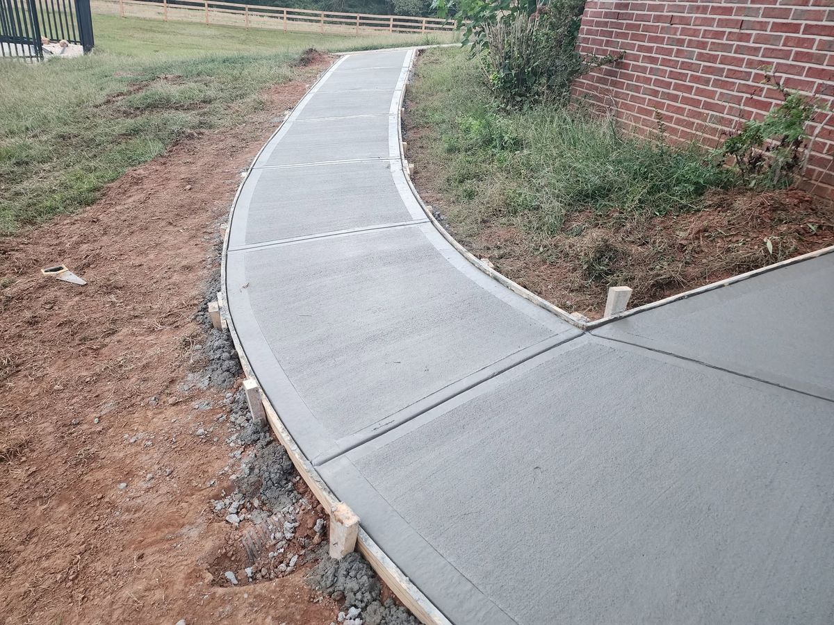 Curved walkway in fresh concrete along the side of a house