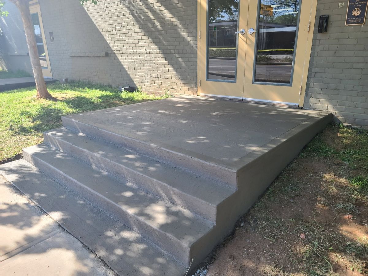 Concrete steps freshly poured at a brick building's back door