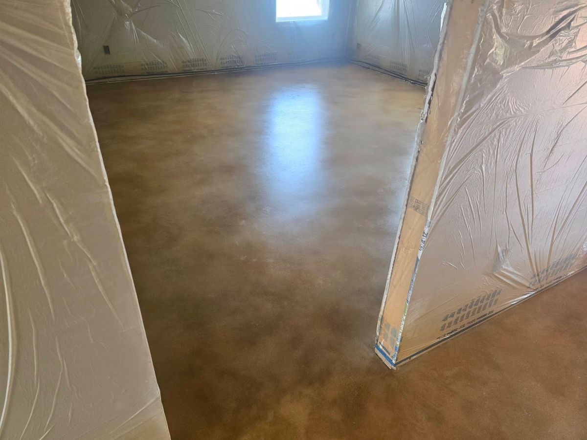 Plastic-sheeted walls around a freshly stained concrete floor