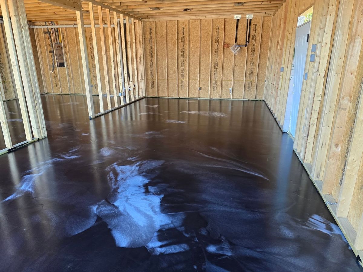 Dark metallic epoxy floor inside a room still in framing