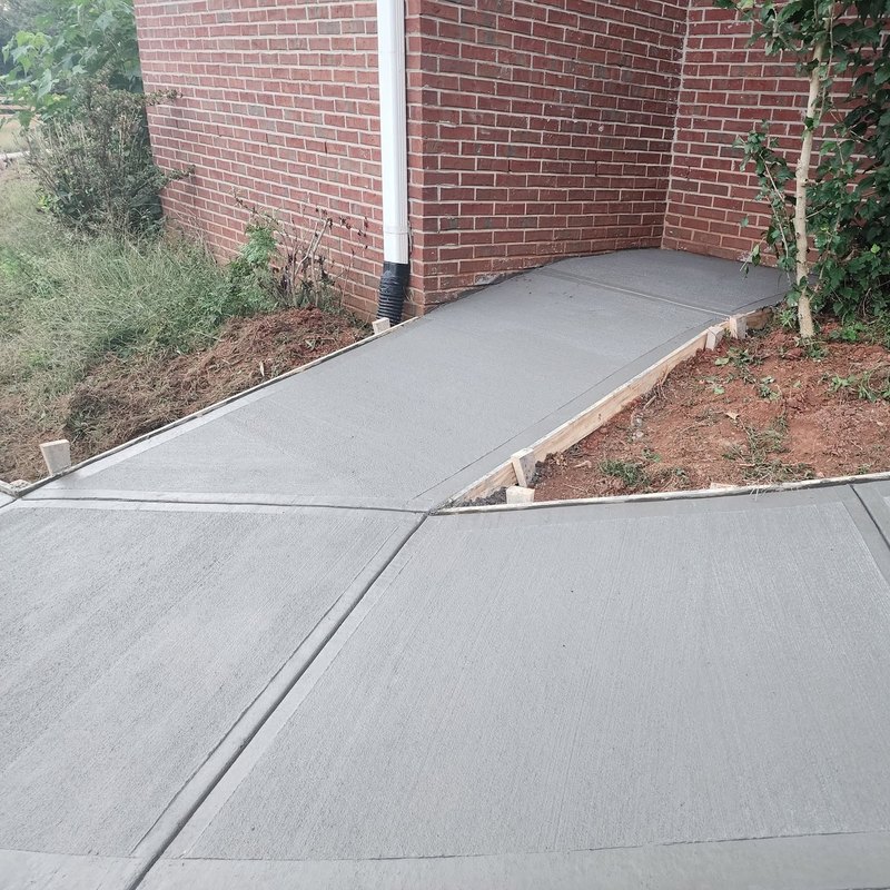 Freshly poured concrete wrapping the corner of a brick home