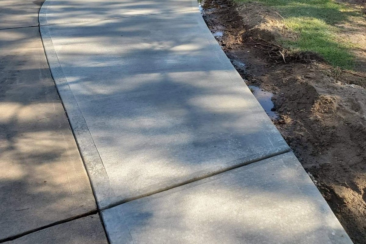 Curved concrete driveway panel with a fresh-cut edge along the lawn