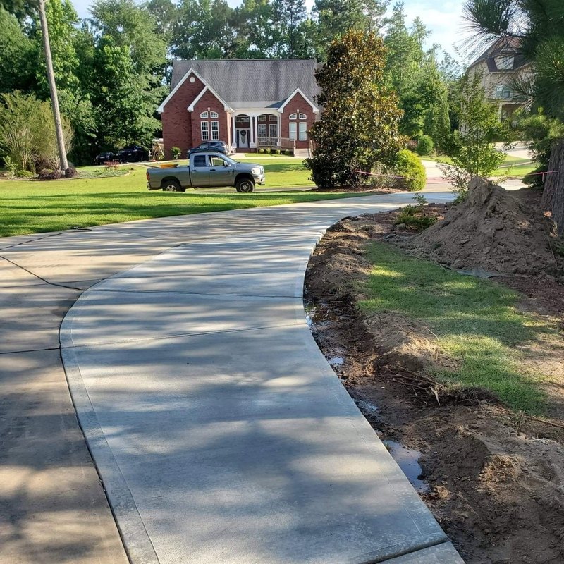 Fresh curved driveway panel edged by lawn and turned soil