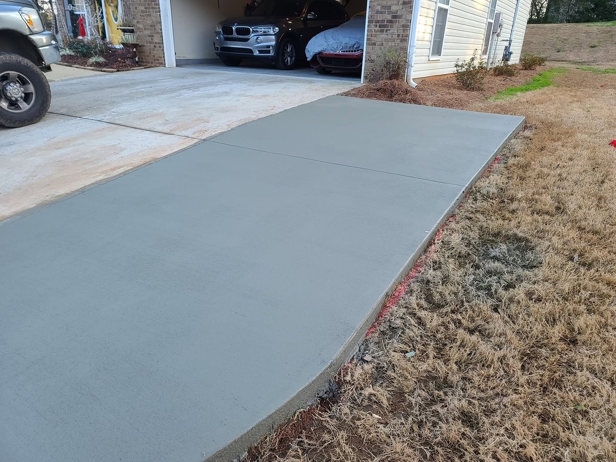Wide new concrete driveway leading to an attached two-car garage