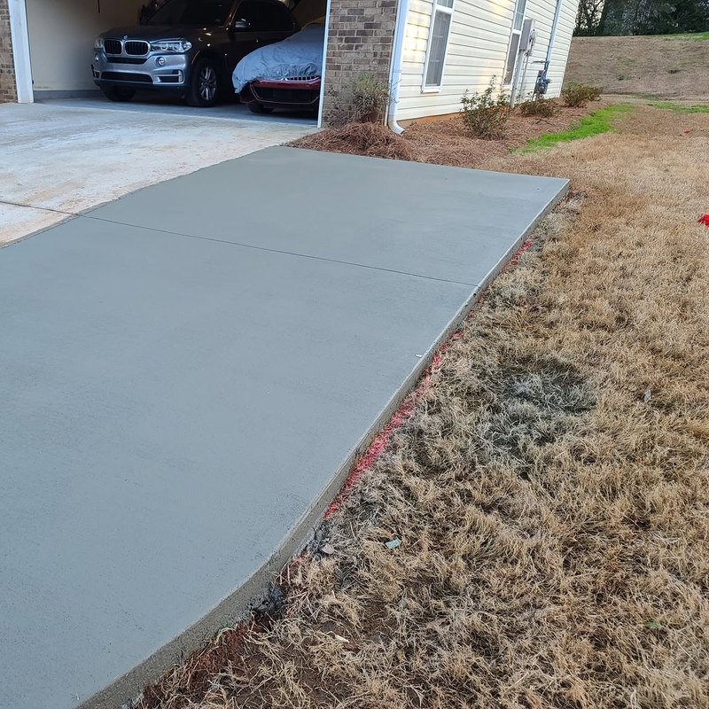 Freshly poured double-wide driveway with two parked cars at the top