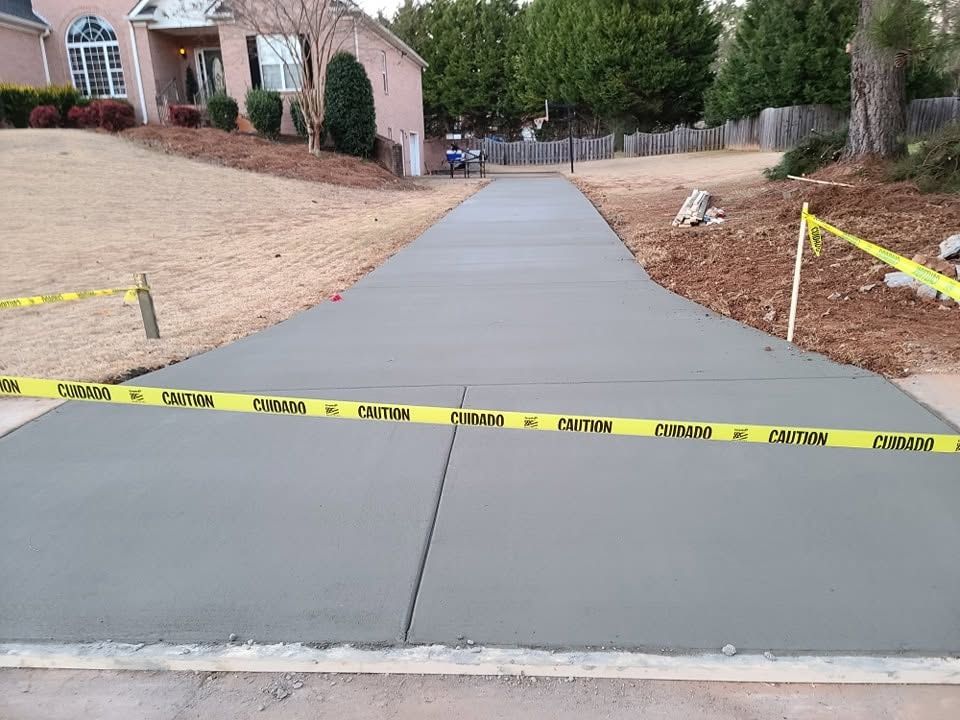 Freshly poured concrete driveway running up to a brick home behind caution tape