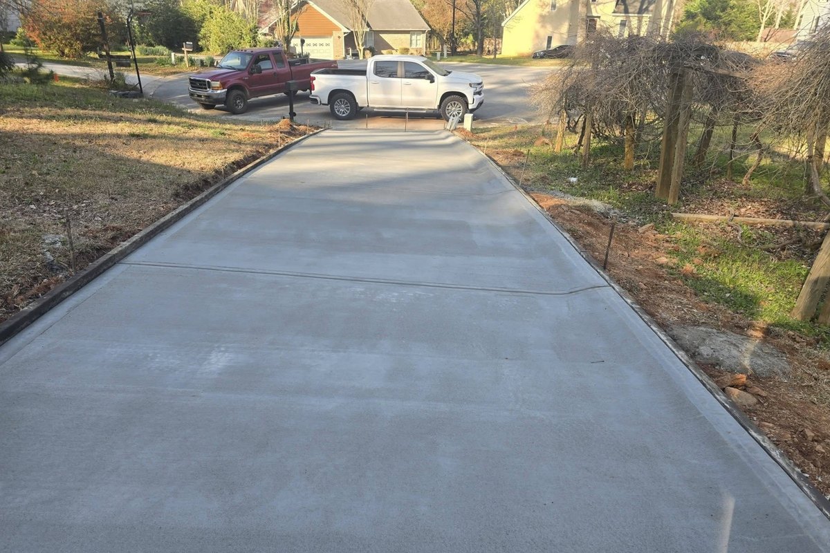 New concrete driveway running down to the street with two pickups at the bottom
