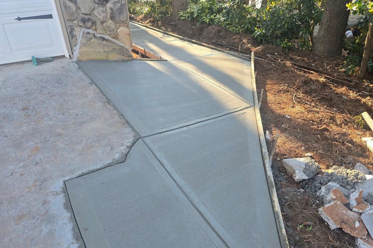 Concrete driveway poured on a slope beside a wooded yard
