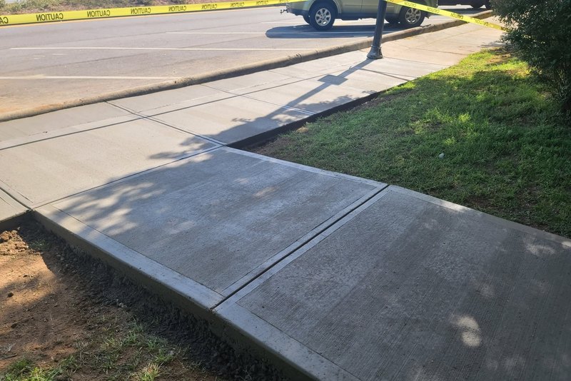 Concrete sidewalk crossing a driveway apron at the street