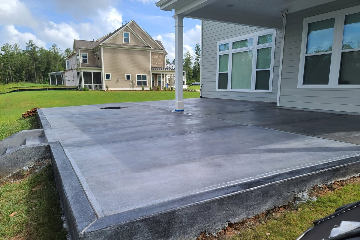 New concrete patio slab poured behind a house