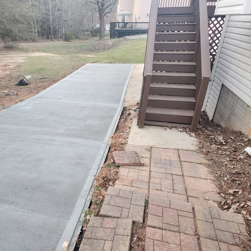 Deck stairs and a paver walk beside a new concrete driveway