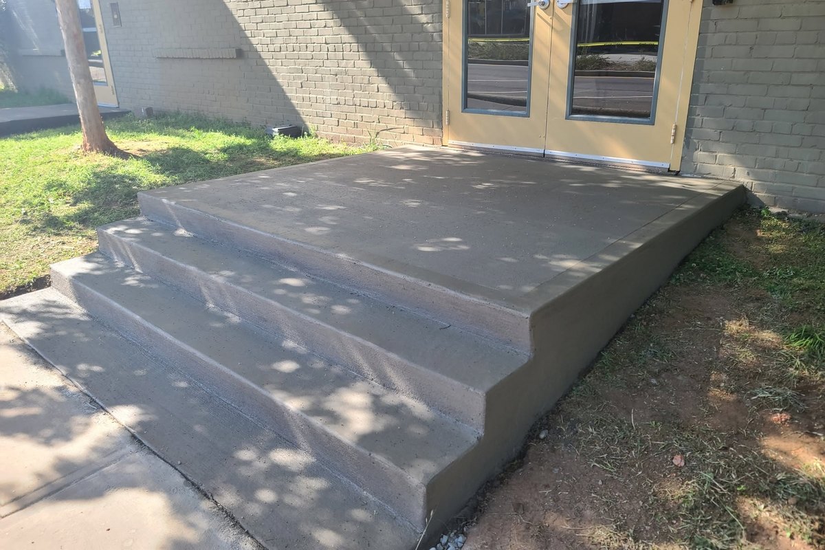 New concrete steps at the back door of a brick building