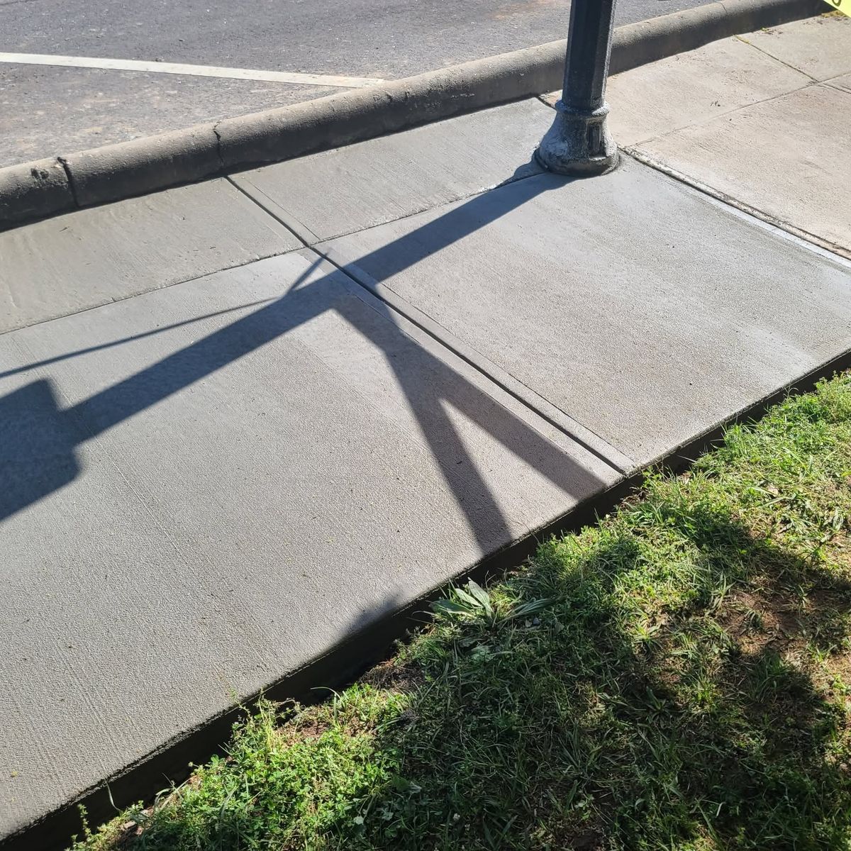 Concrete sidewalk running beside a new curb at the street