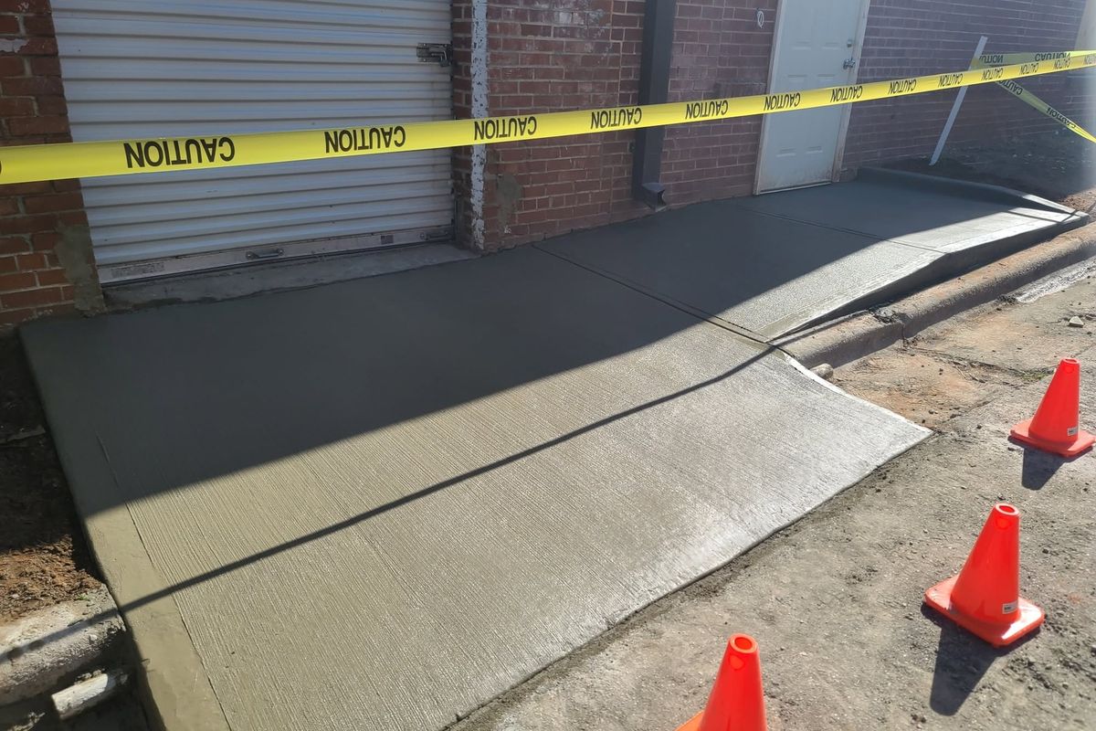 Replaced sidewalk sections beside a building behind caution tape