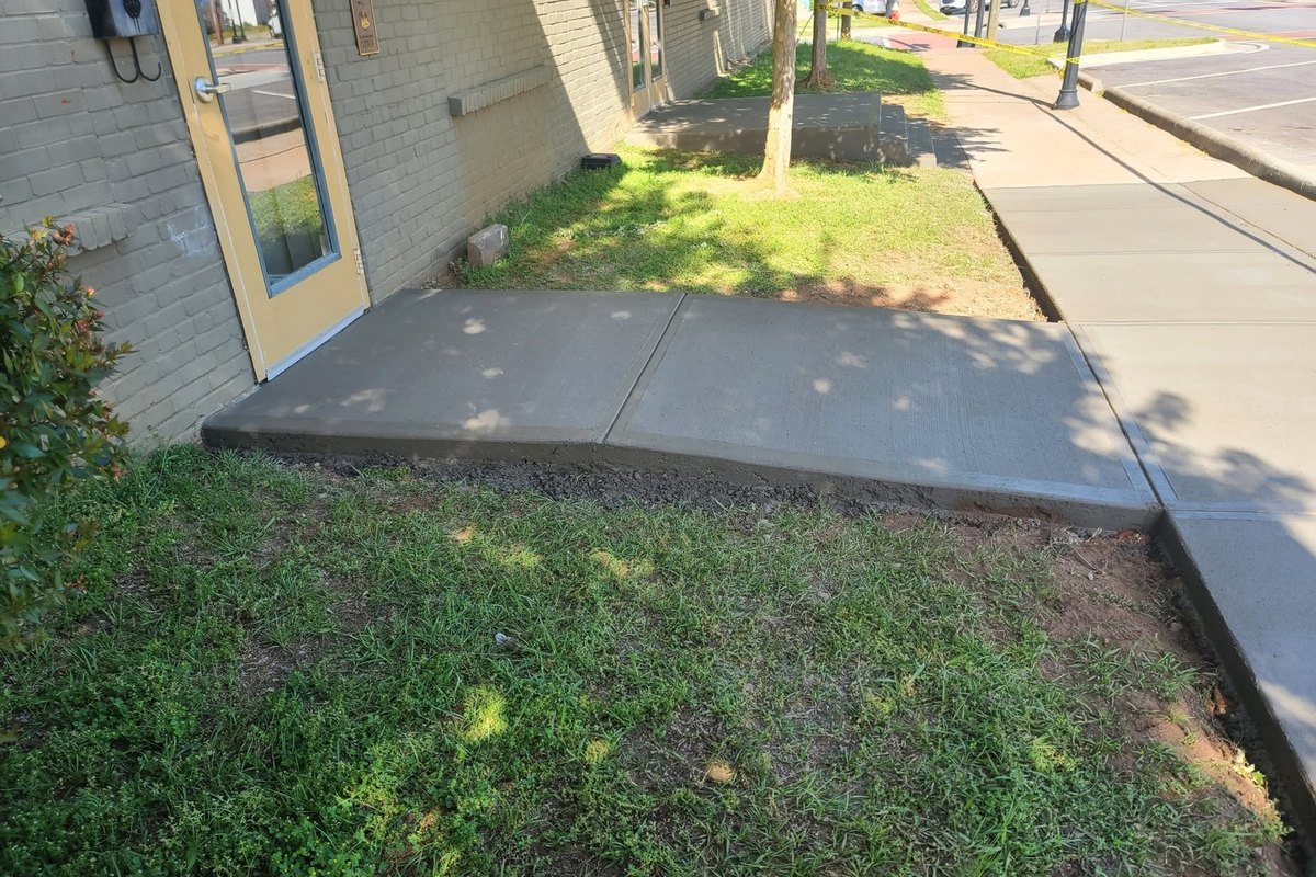 Concrete sidewalk running past the corner of a yellow brick building