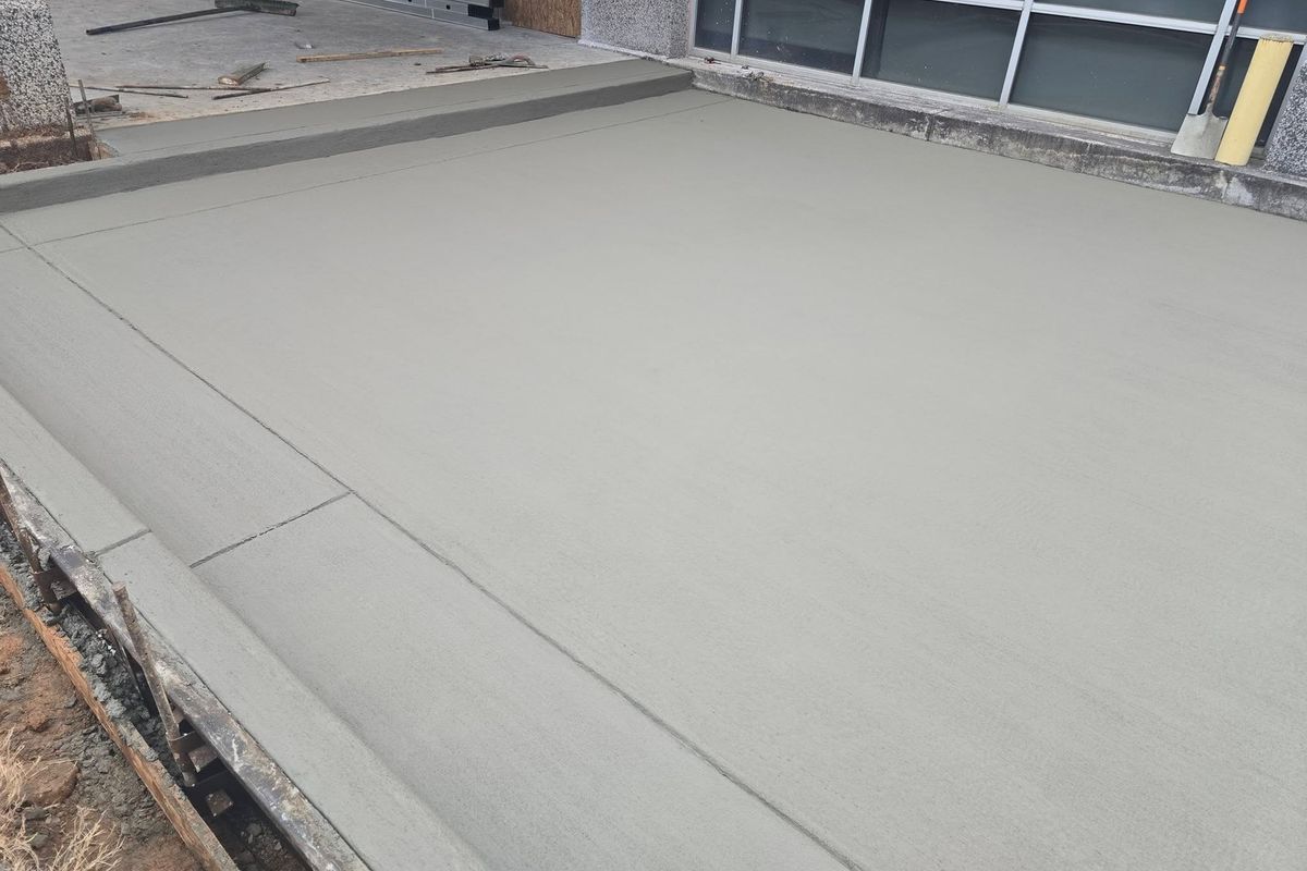 Freshly placed commercial concrete slab beside a building's window wall