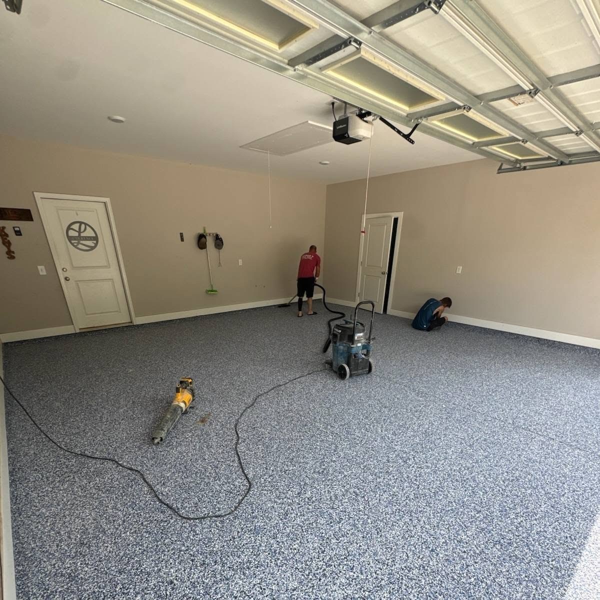 Crew member running a floor grinder in a garage before coating