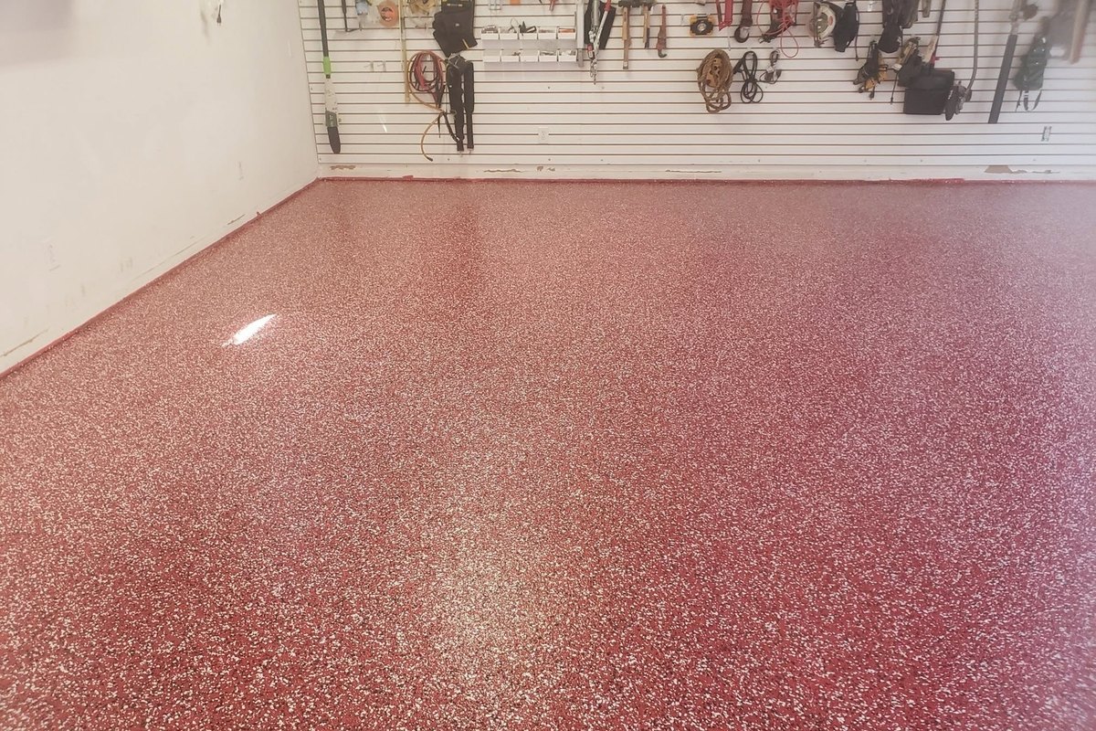 Red and black flake epoxy floor in a home garage with a tool wall