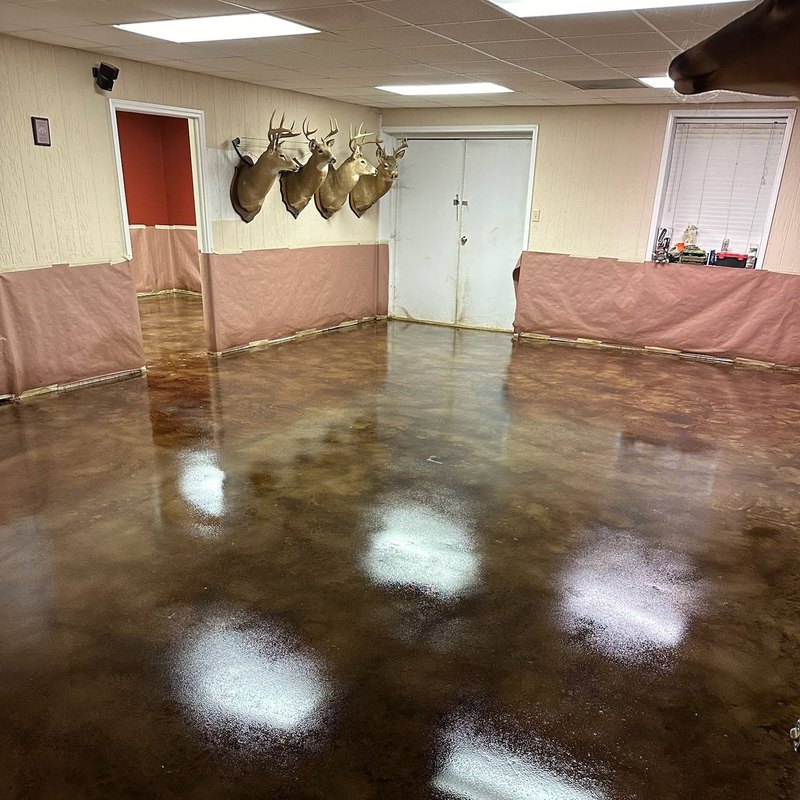 Amber stained concrete floor at a doorway with plastic on the walls