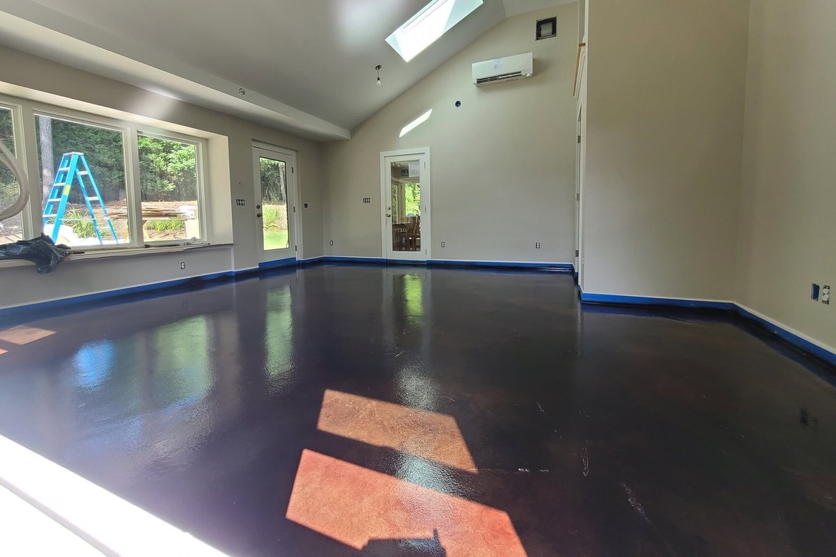 Dark stained and sealed concrete floor in a living room with a skylight