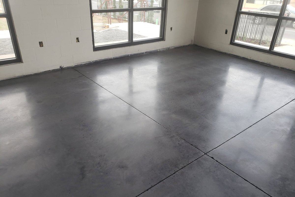 Dark sealed concrete floor in a room with large windows