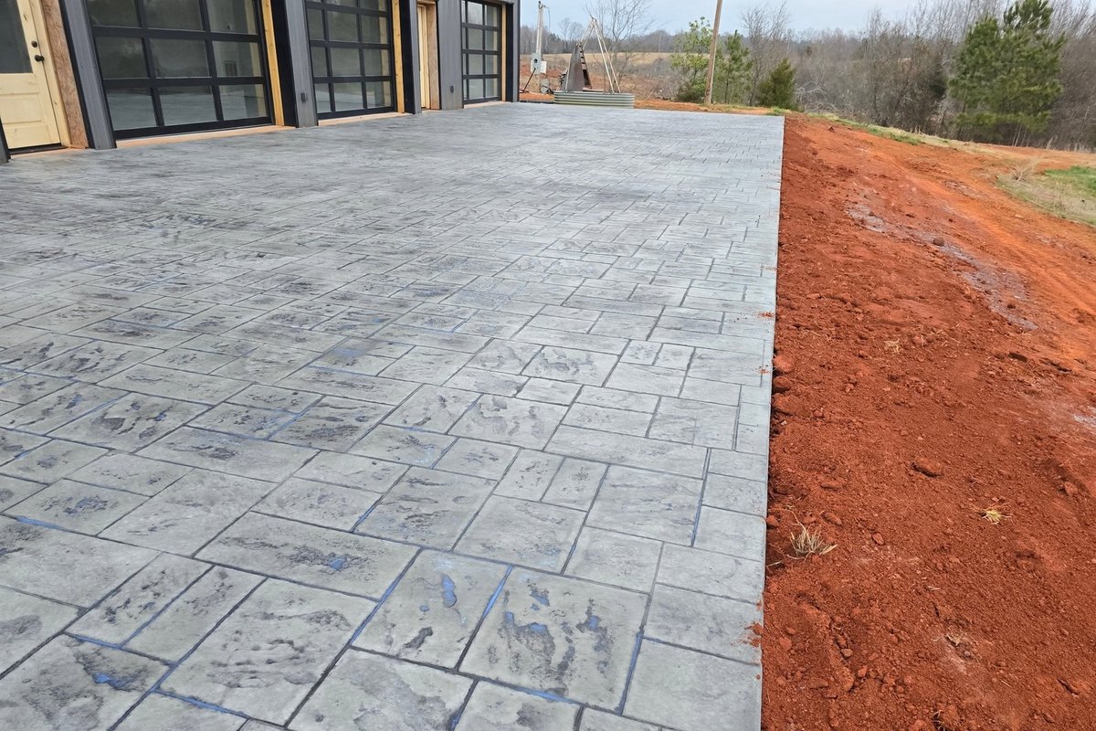 Stamped driveway in an ashlar slate pattern next to graded red clay