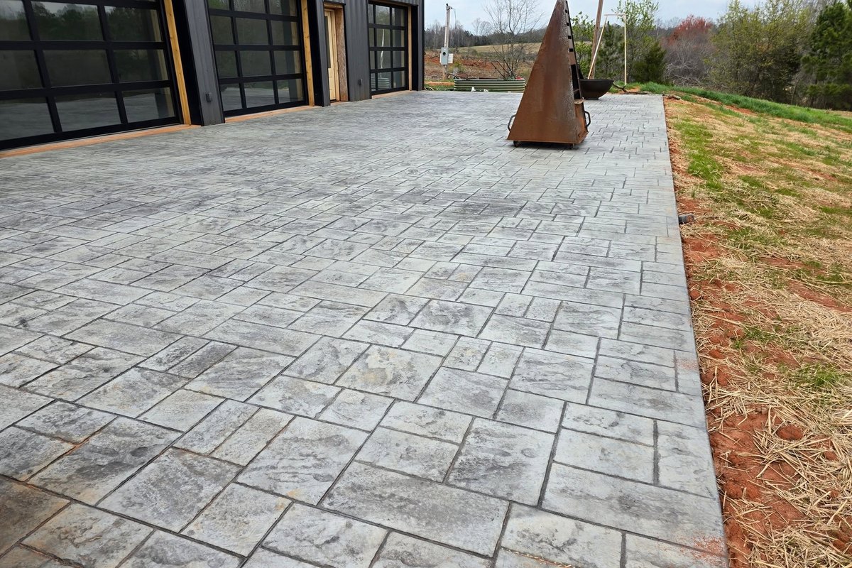 Stamped ashlar patio with a steel sculpture outside a glass-walled home